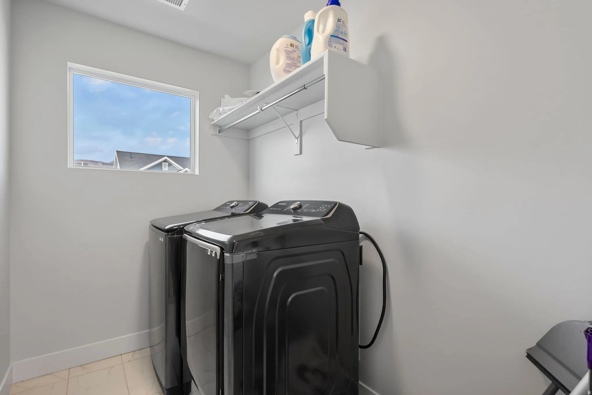 Laundry room featuring washer and dryer and light marble finish flooring