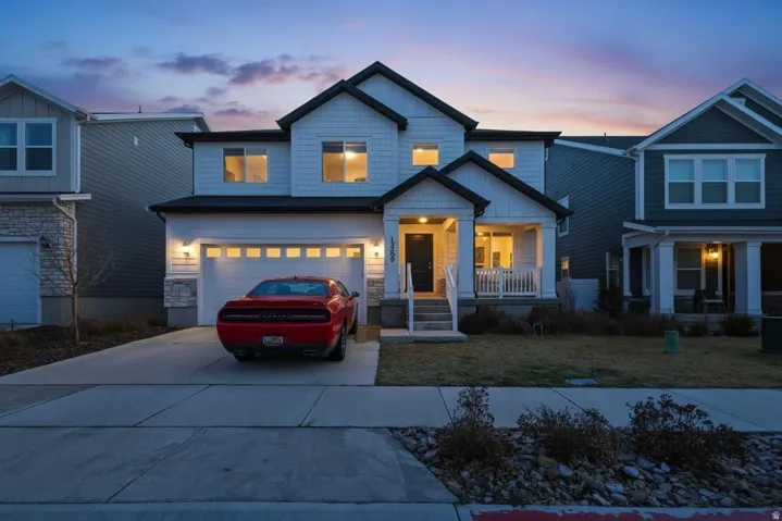 Craftsman-style home with an attached garage, driveway, a front yard, and stone siding