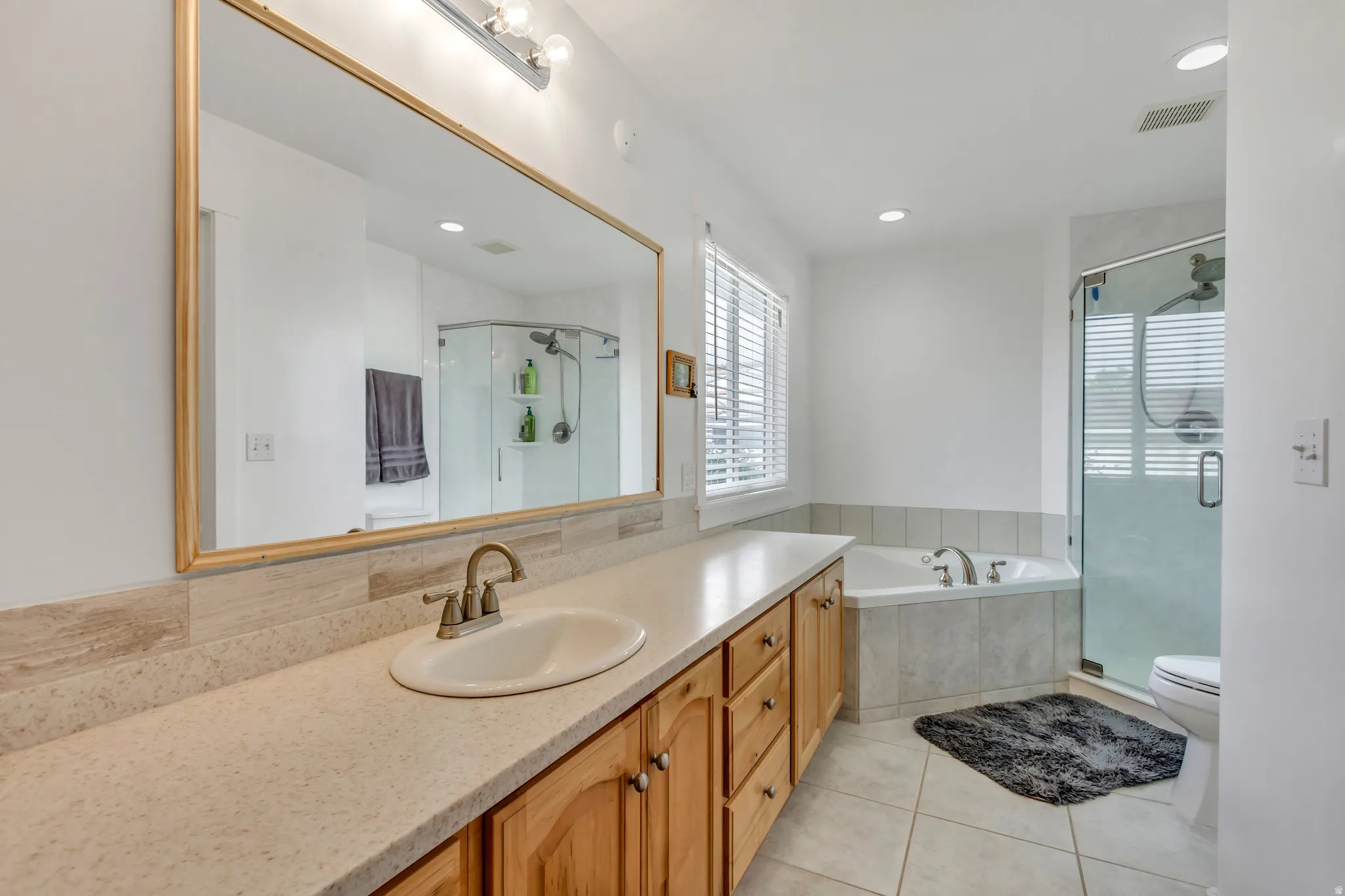 Bathroom with a stall shower, vanity, a garden tub, light tile patterned floors, and recessed lighting
