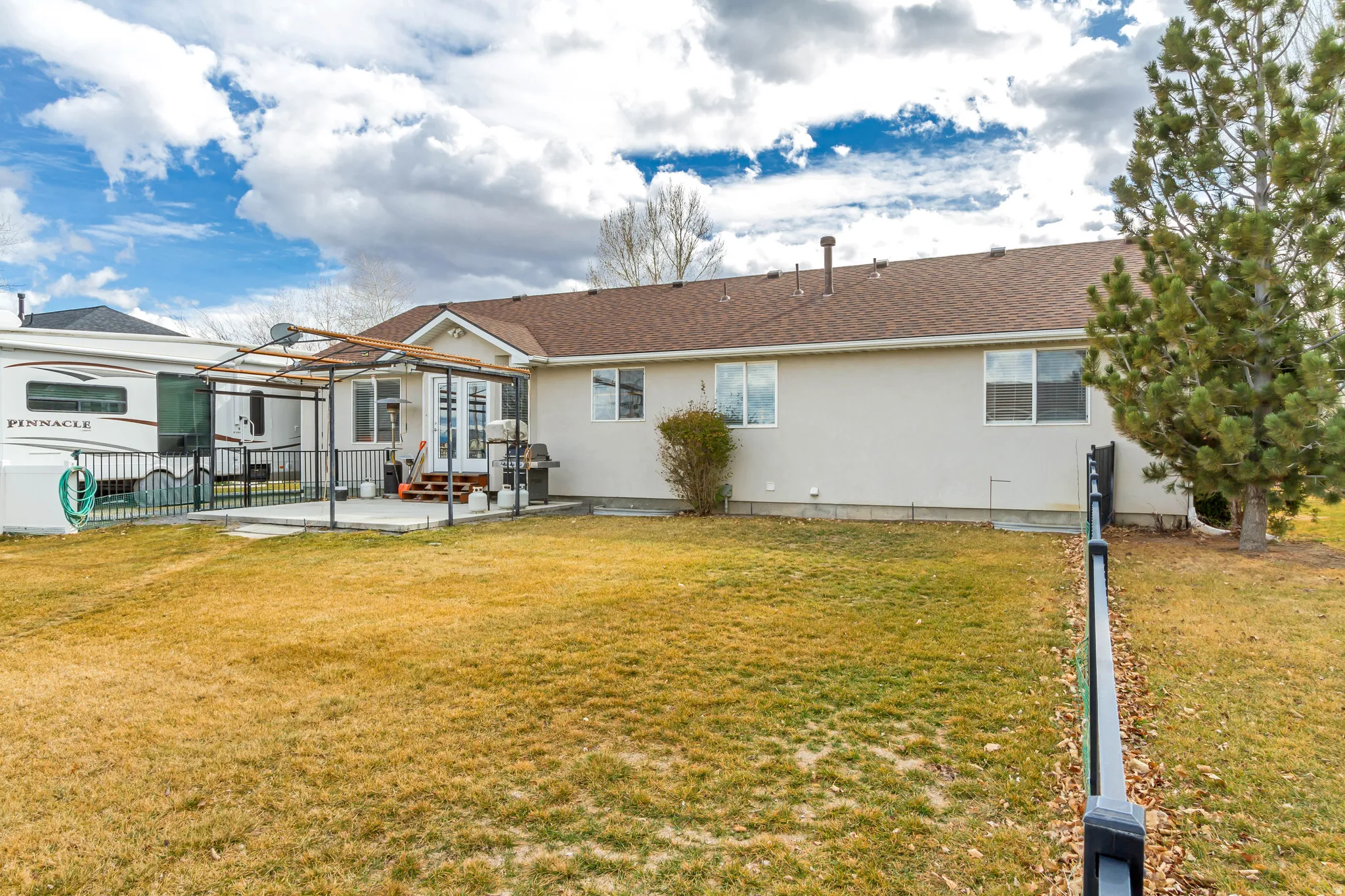 Back of property with a patio, stucco siding, and a shingled roof