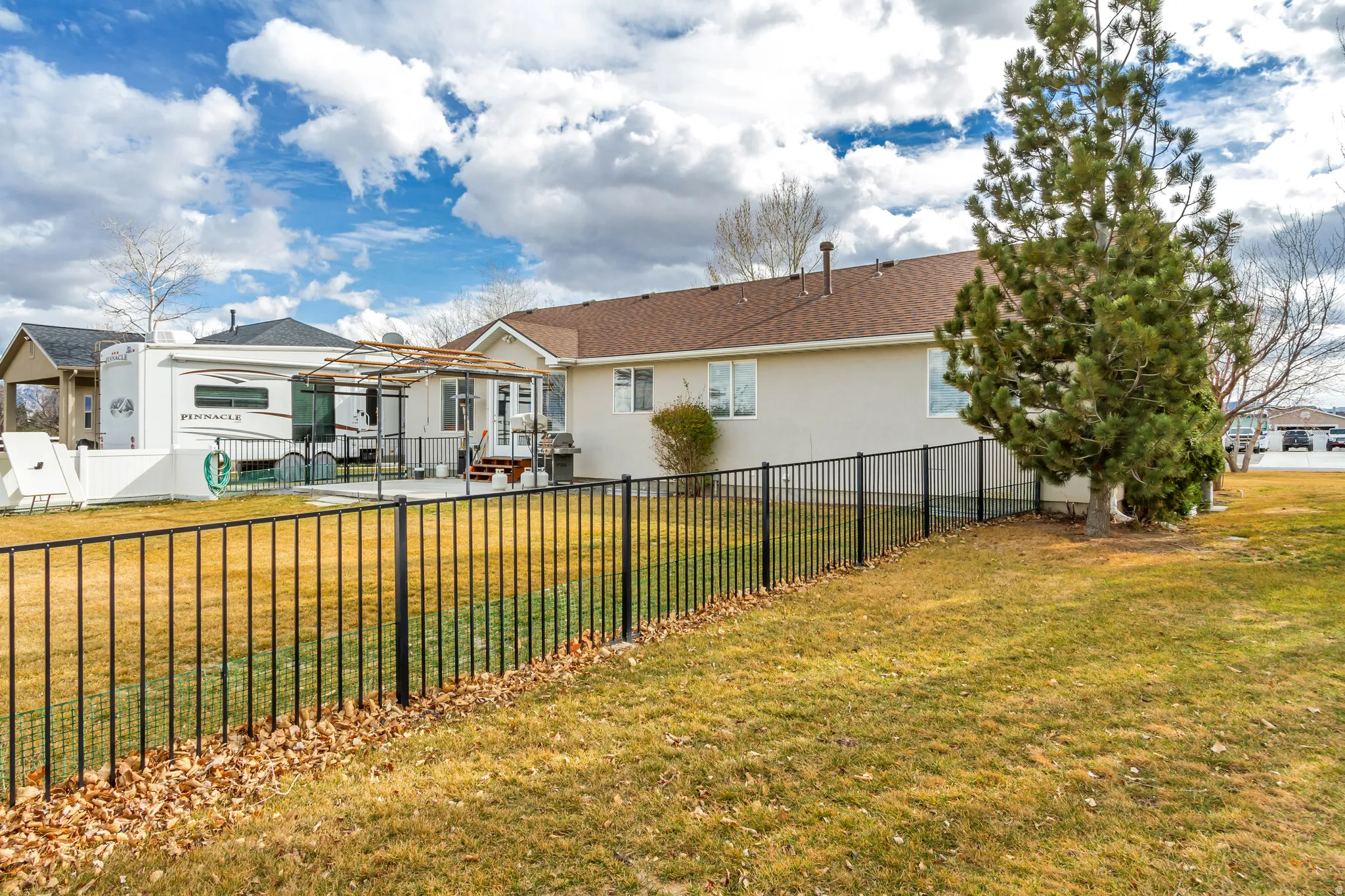 Back of house with stucco siding, a residential view, and a patio