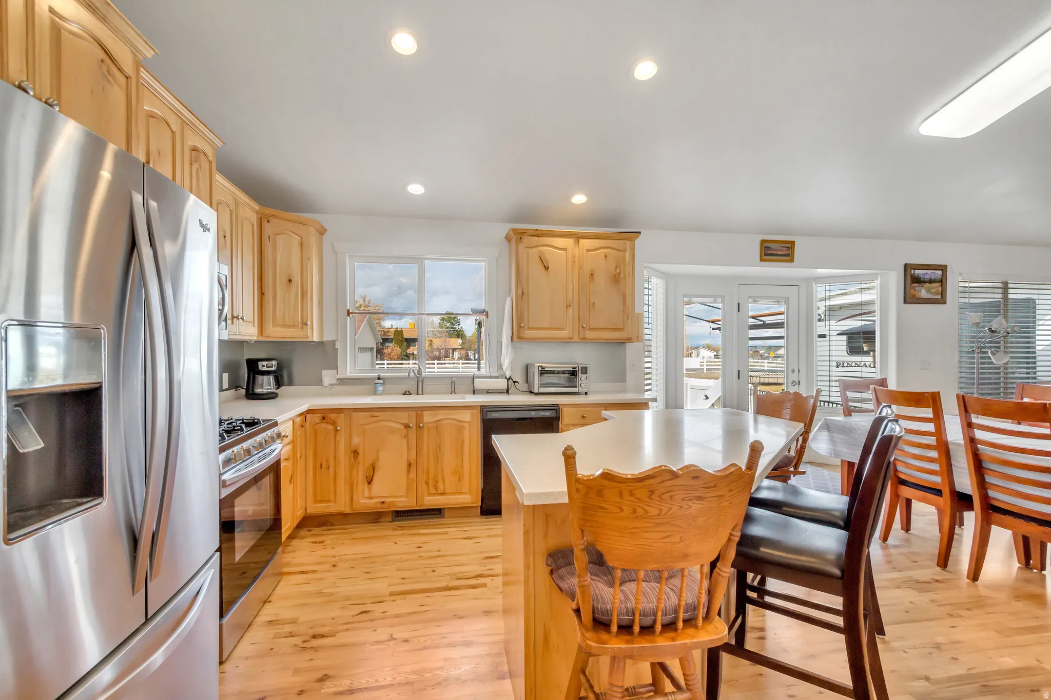 Kitchen with light wood finish cabinets, stainless steel appliances, light countertops, light wood-style floors, and a center island