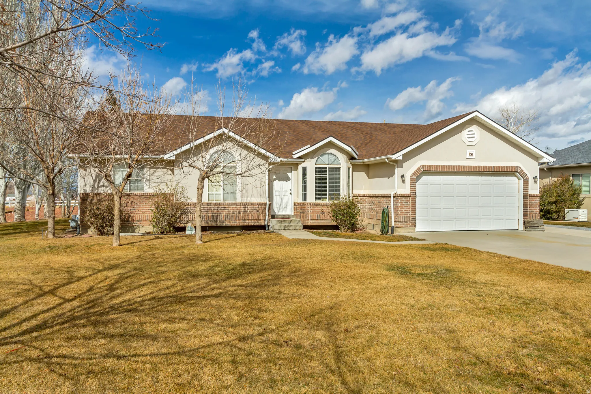 Ranch-style house featuring brick siding, a garage, a front lawn, and driveway