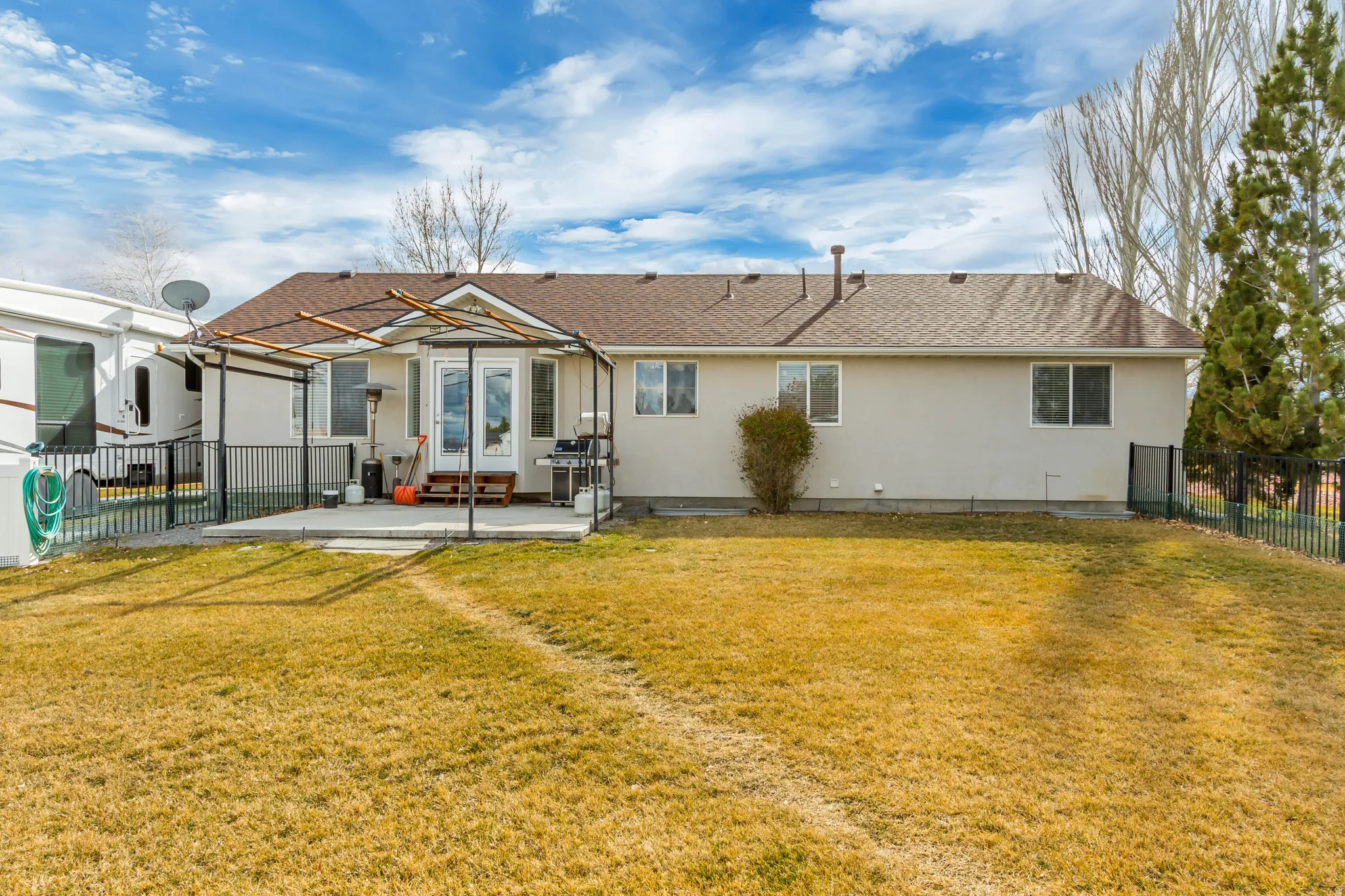 Rear view of property with a fenced backyard, a patio, stucco siding, and roof with shingles