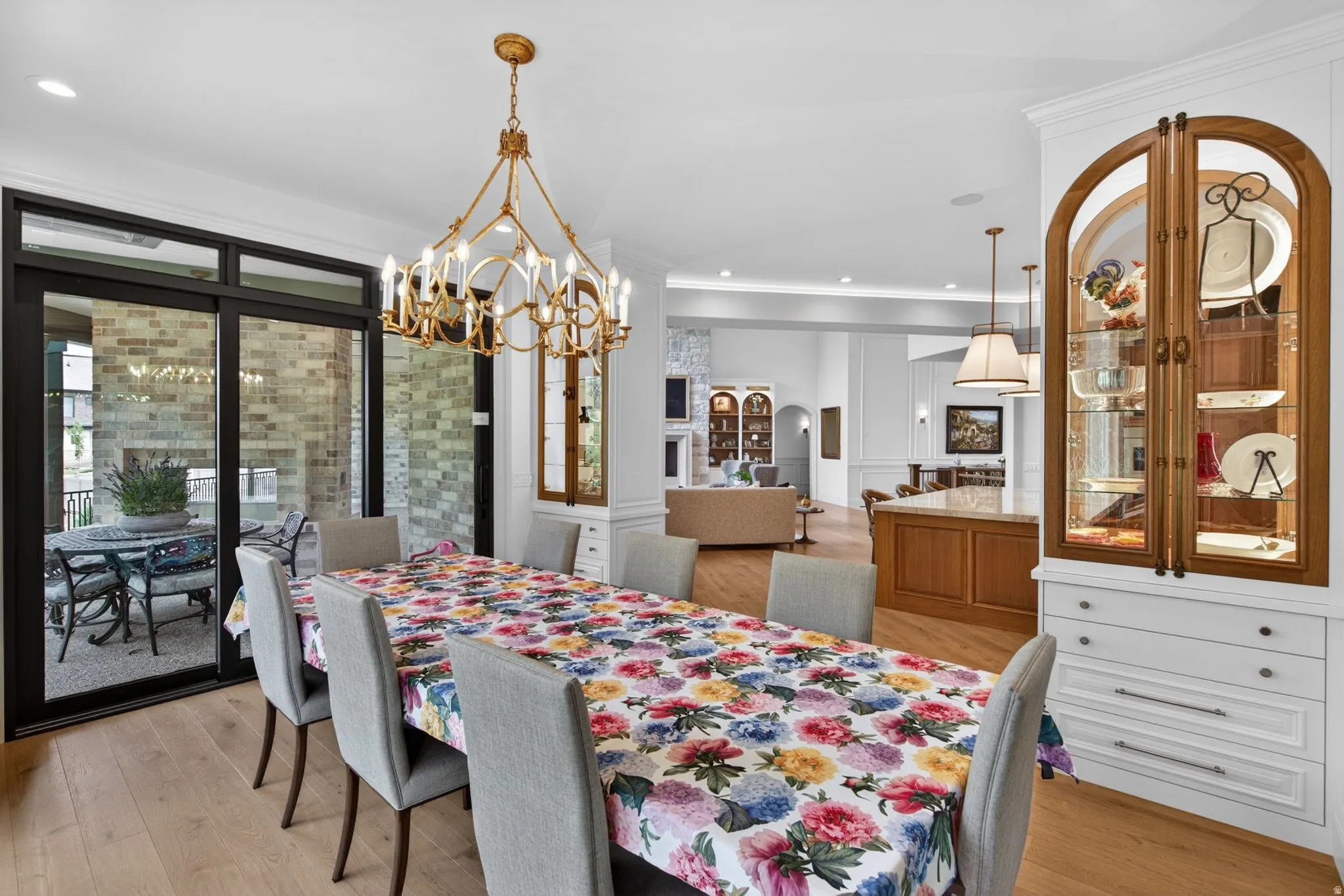 Expansive dining area featuring wood-finish flooring and a decorative chandelier flanked by custom decorative display cabinets