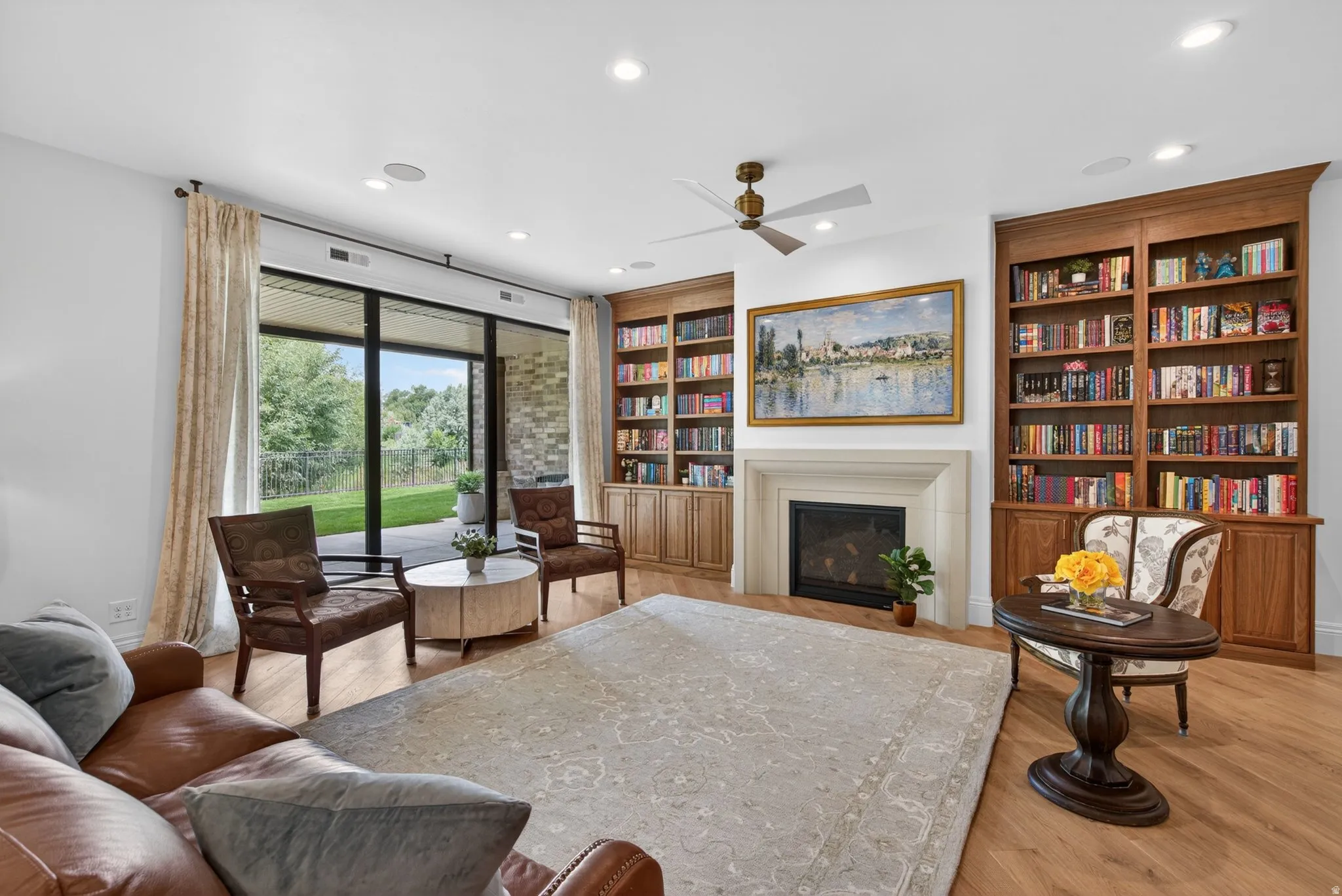 Spacious living area featuring oak flooring, built-in shelving, gas fireplace
