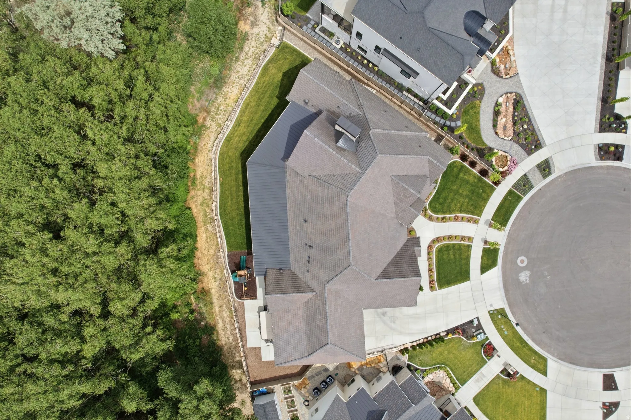 Aerial perspective showcasing a contemporary residence with a multi-pitched roof with bar tile, manicured lawn, and paved driveway