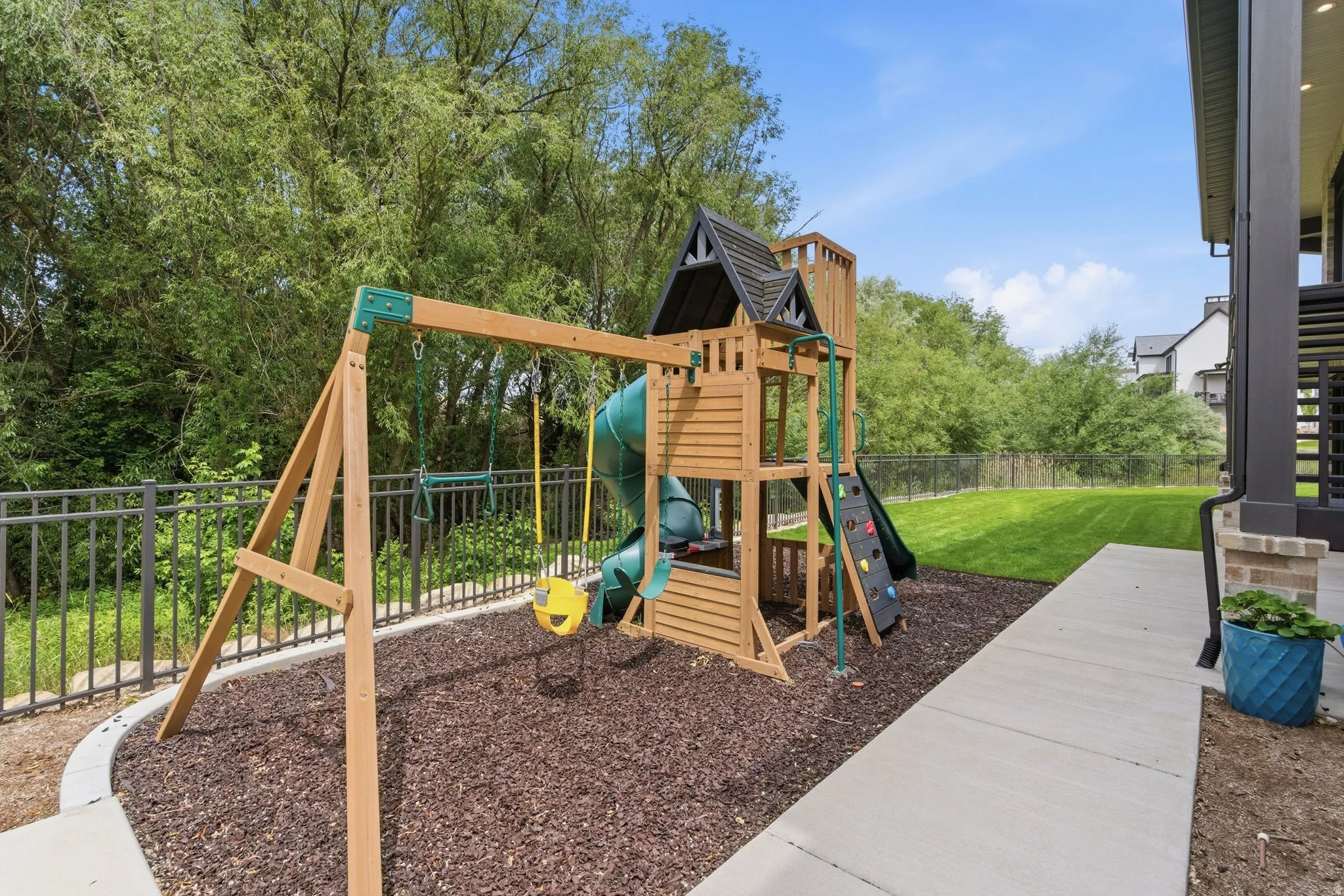 Expansive outdoor area featuring a wooden playset with swings, slide, and climbing wall