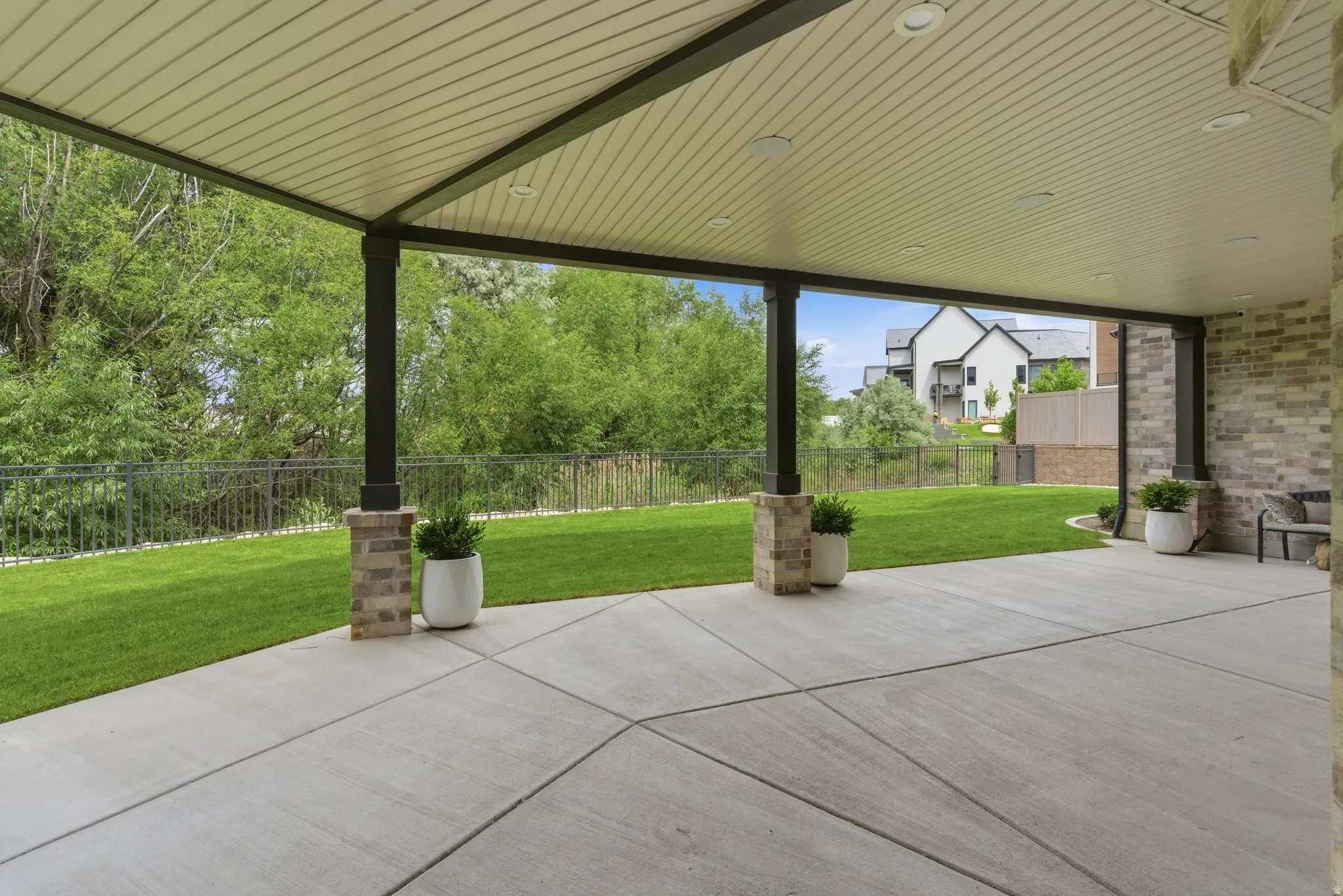 Covered patio with recessed lighting, concrete flooring, and brick-wrapped columns