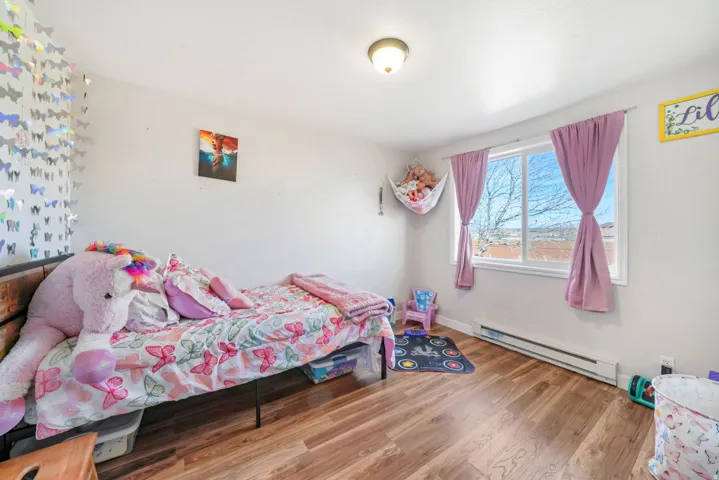 Bedroom with a baseboard heating unit and wood finished floors