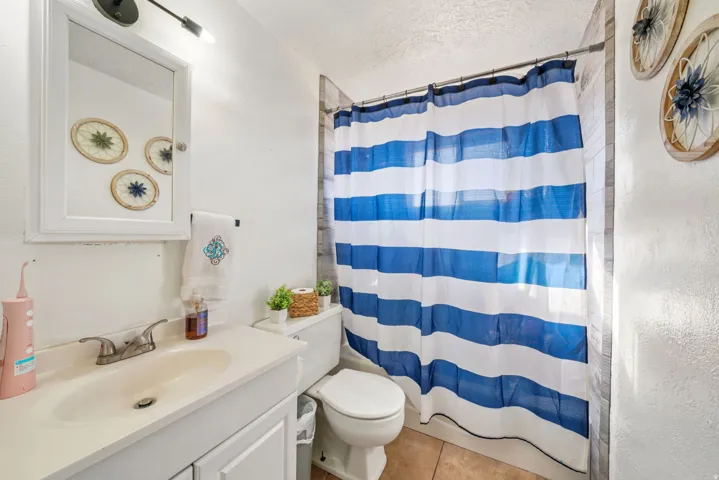 Full bath featuring vanity, light tile patterned floors, and a textured ceiling