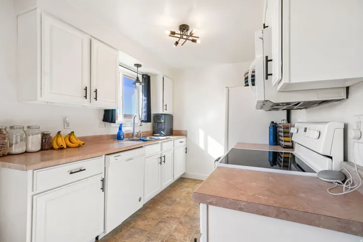 Kitchen with white cabinetry, white appliances, and light countertops