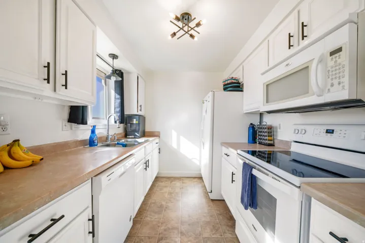 Kitchen featuring white appliances, white cabinets, and light countertops