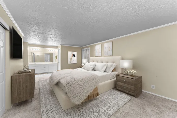 Bedroom with crown molding, light carpet, a textured ceiling, and ensuite bath