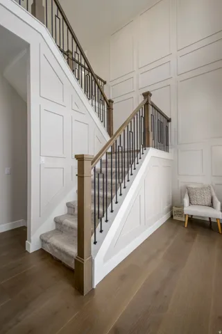 Stairway with a decorative wall, wood finished floors, and a high ceiling