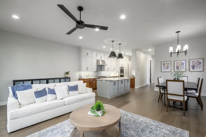 Living room with light wood finished floors, ceiling fan, and hanging lights