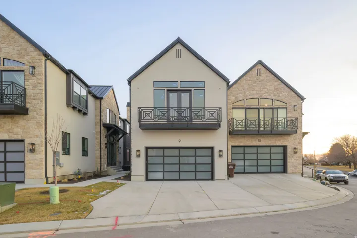 Contemporary home with an attached garage, stucco siding, driveway, a balcony, and stone siding