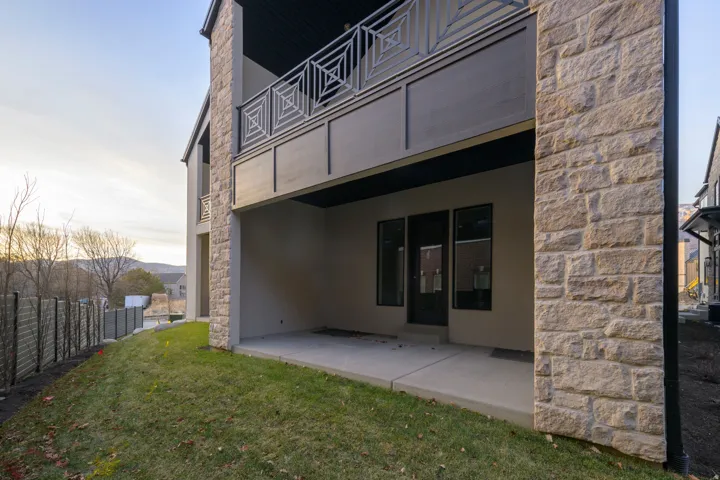 Back of house featuring stone siding, a patio, and stucco siding