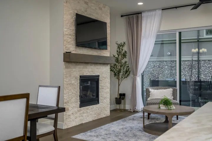 Living area featuring a stone fireplace and dark wood-style floors
