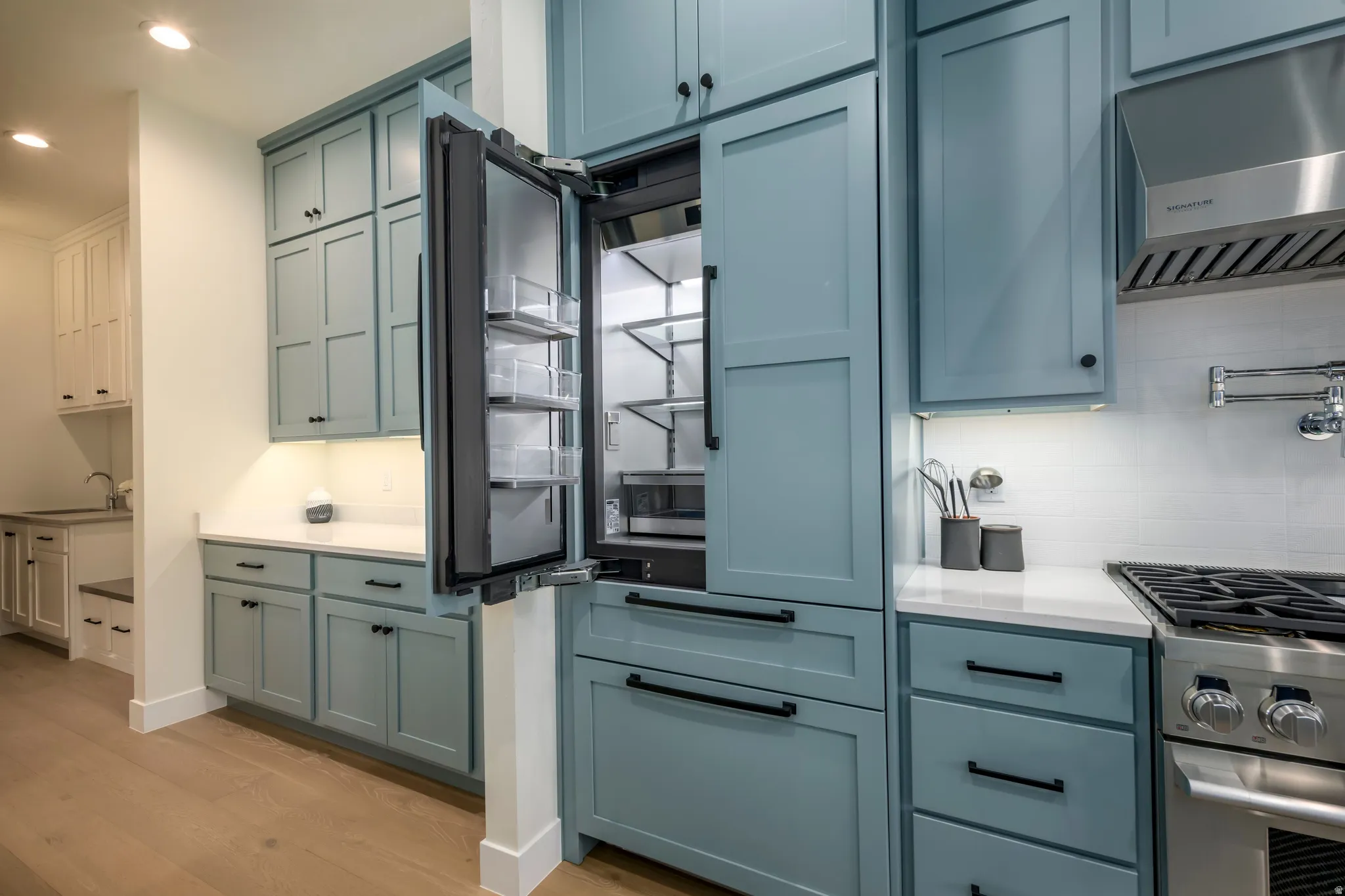 Kitchen featuring gas range, light wood-style floors, paneled built in refrigerator, recessed lighting, and blue cabinetry