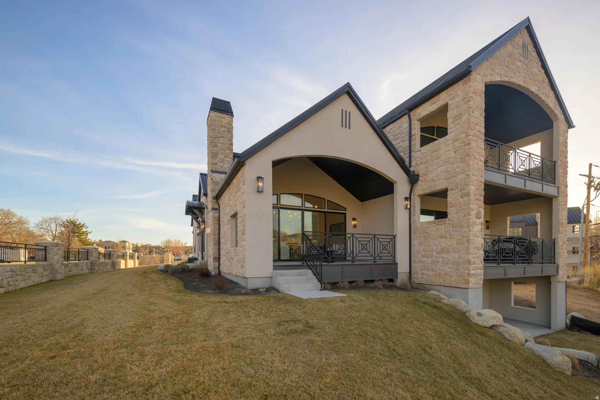 Rear view of property featuring stucco siding, a yard, stone siding, and a chimney