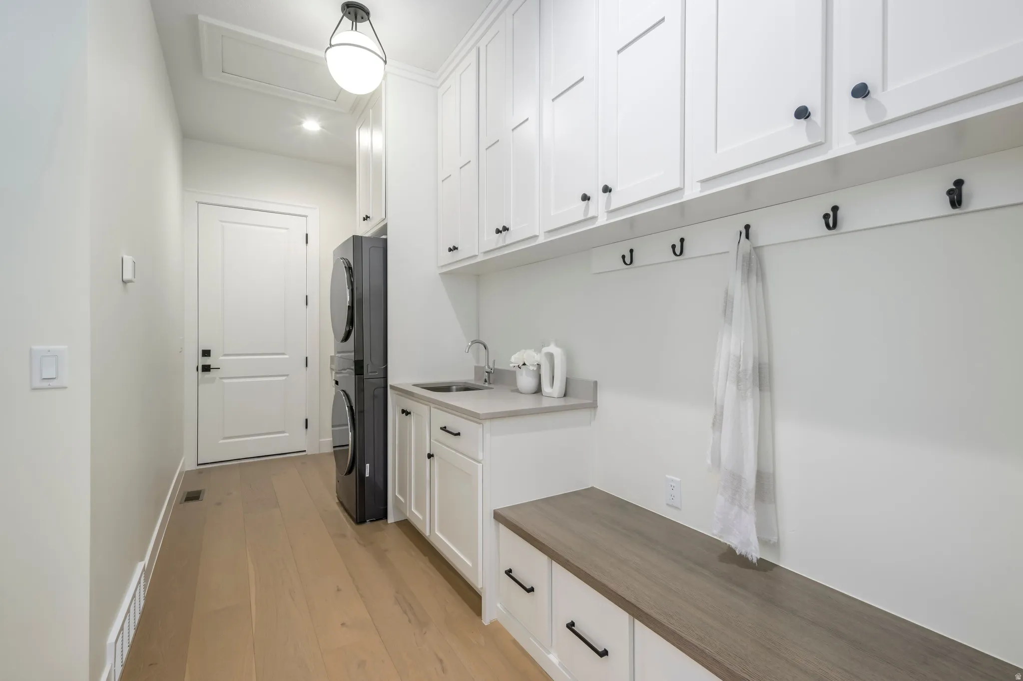 Mudroom with stacked washing machine and dryer and light wood-style flooring