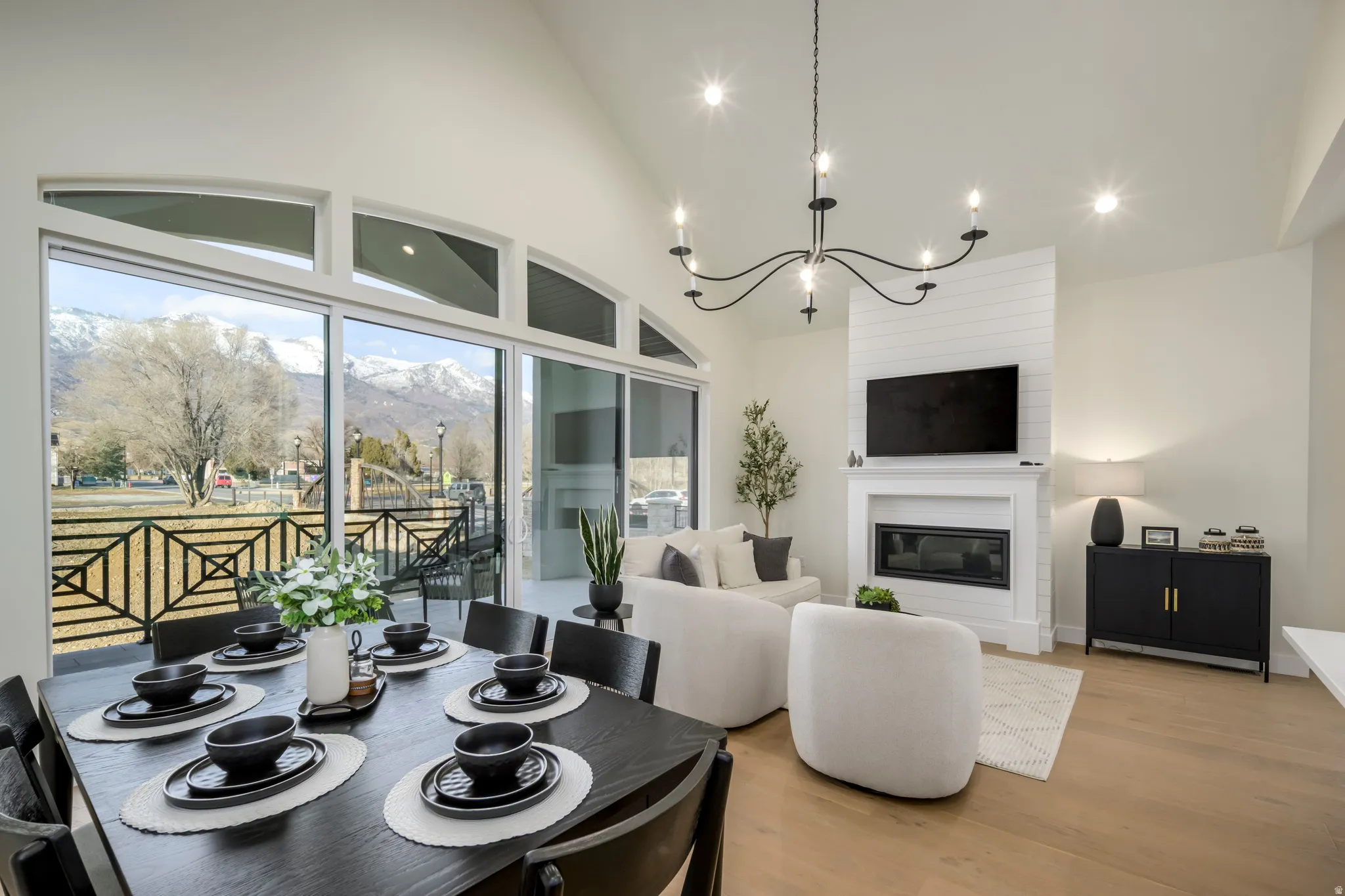 Dining area with light wood-style flooring, suspended lighting, vaulted ceiling, and a large fireplace