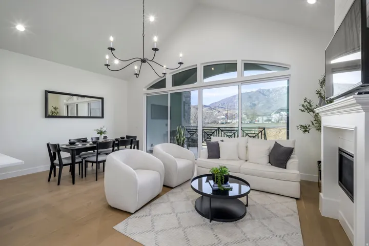 Living area with lofted ceiling, wood finished floors, a glass covered fireplace, and suspended lighting