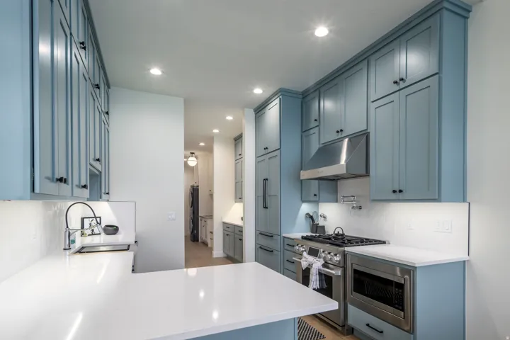 Kitchen featuring decorative backsplash, light stone countertops, stainless steel appliances, a peninsula, and recessed lighting