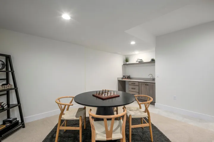 Dining room with recessed lighting, bar with sink, and light colored carpet