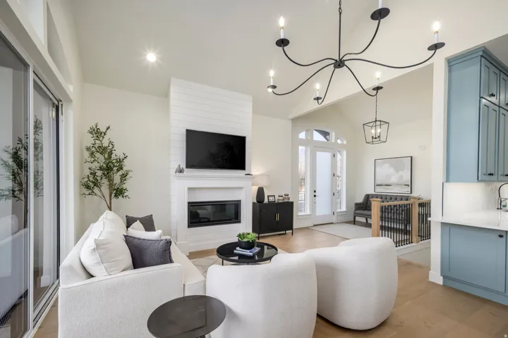 Living room with light wood-style floors, a large fireplace, a chandelier, and vaulted ceiling