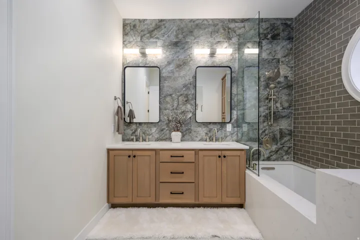 Bathroom featuring double vanity, bathing tub / shower combination, and tile walls