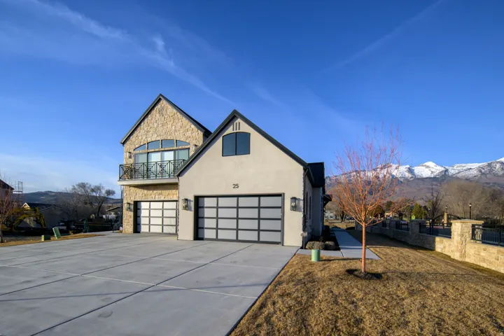 View of front of home with stone siding, a mountain view, concrete driveway, and an attached garage