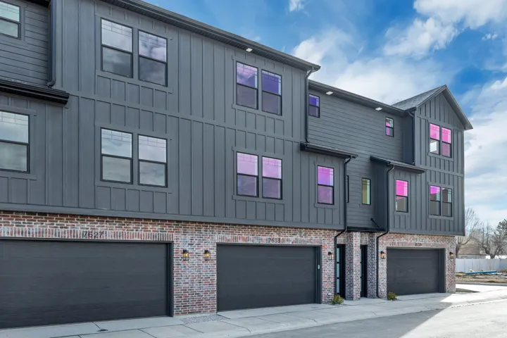 View of property exterior featuring board and batten siding, a garage, and brick siding