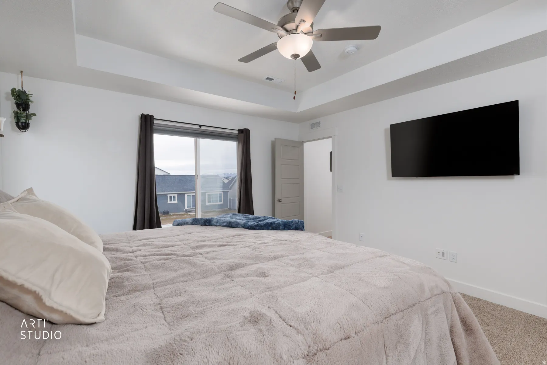 Bedroom featuring a raised ceiling, carpet floors, and a ceiling fan