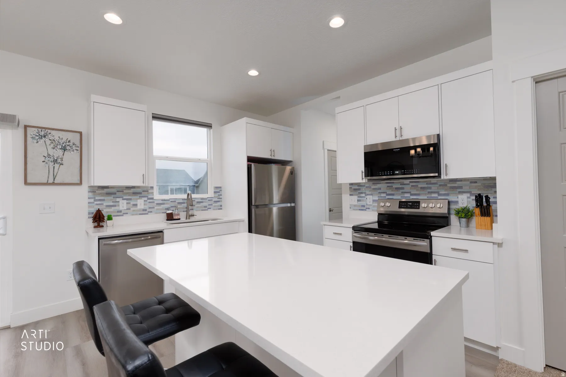 Kitchen with stainless steel appliances, white cabinets, backsplash, a breakfast bar, and a kitchen island