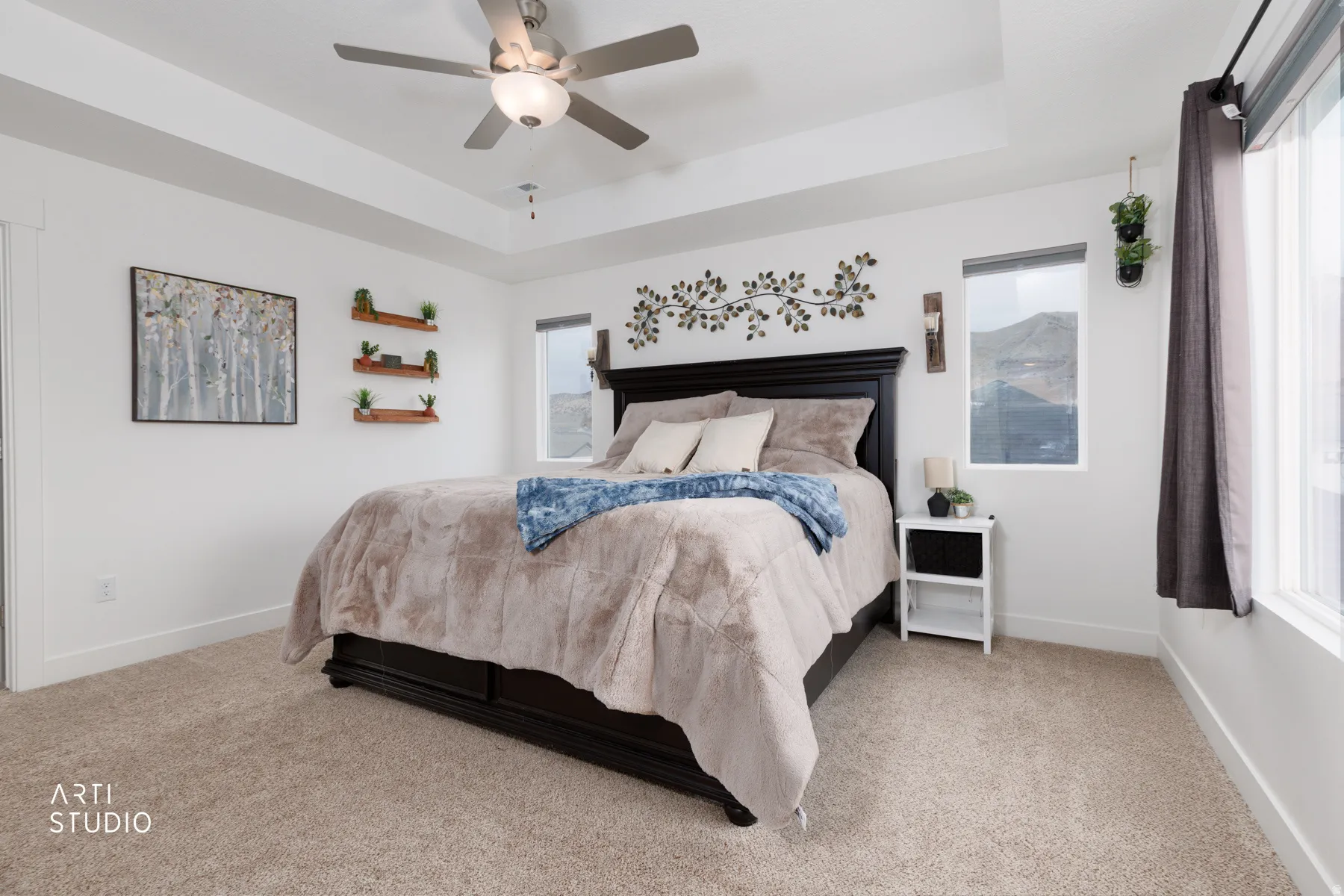 Bedroom with a tray ceiling, light carpet, and ceiling fan