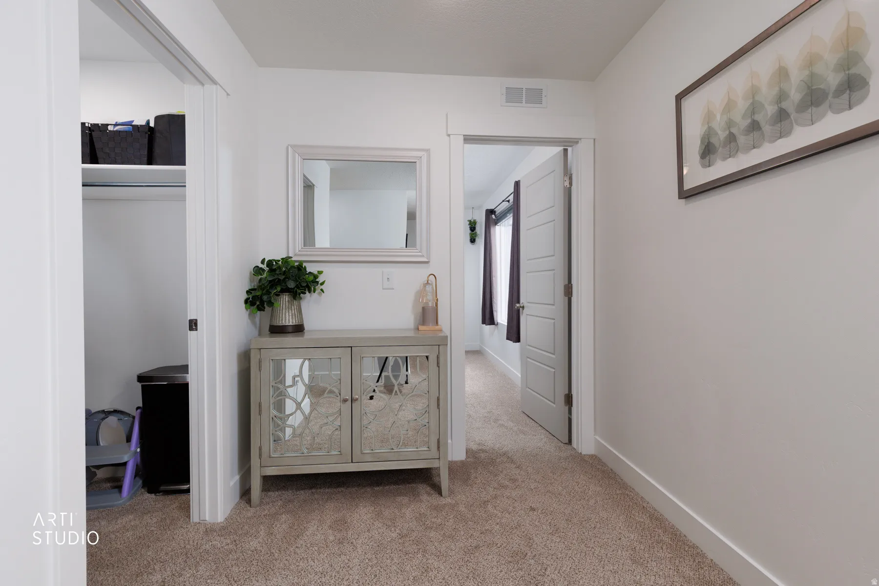 Hall with light colored carpet and baseboards