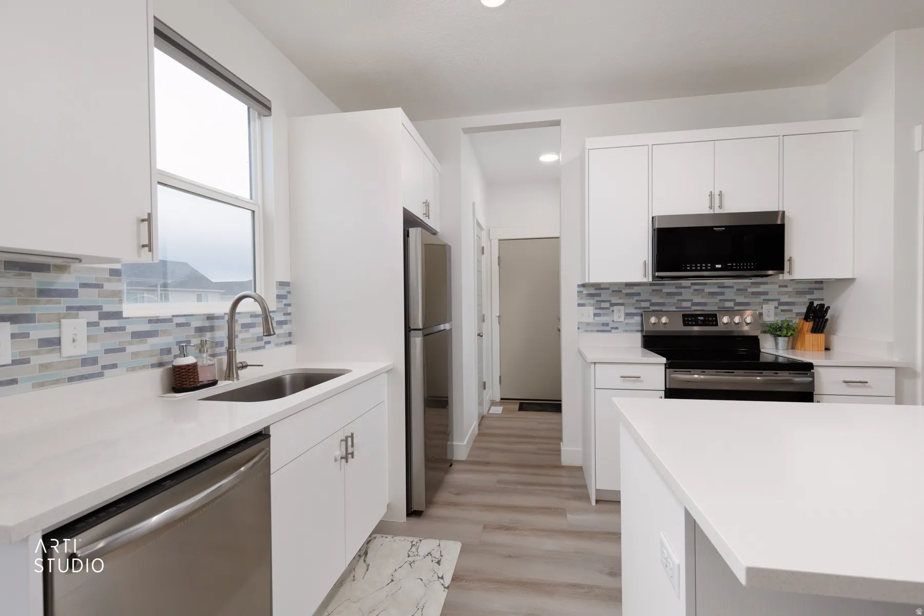 Kitchen featuring white cabinets, stainless steel appliances, and decorative backsplash