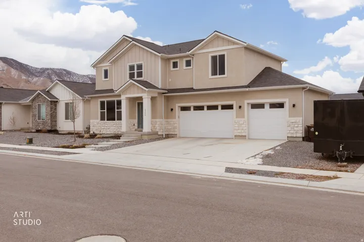 View of front facade with driveway, stone siding, board and batten siding, a mountain view, and a shingled roof