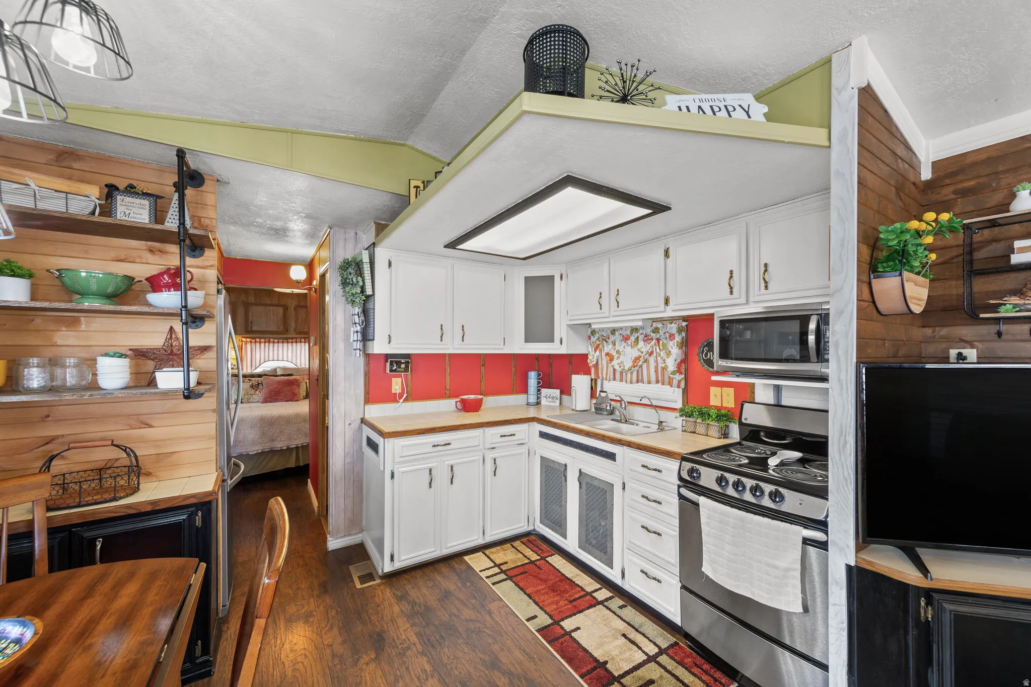 Kitchen featuring white cabinetry, stainless steel appliances, dark wood-style floors, and a textured ceiling