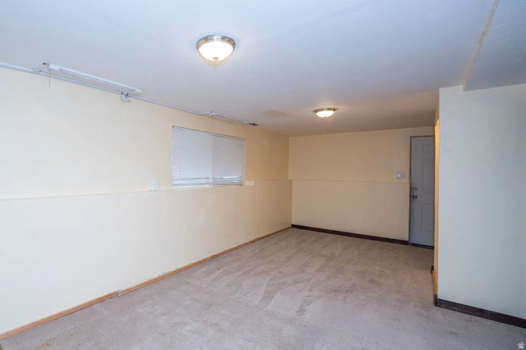 Spare room featuring light carpet and baseboards