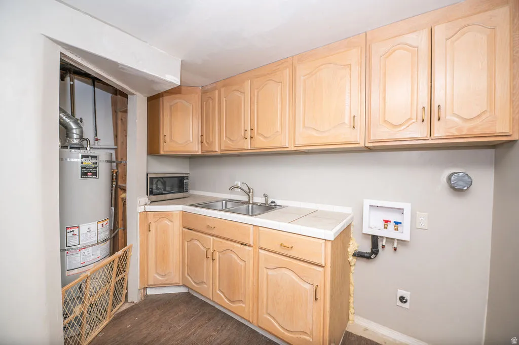 Laundry area with hookup for a washing machine, dark wood-type flooring, cabinet space, and strapped water heater