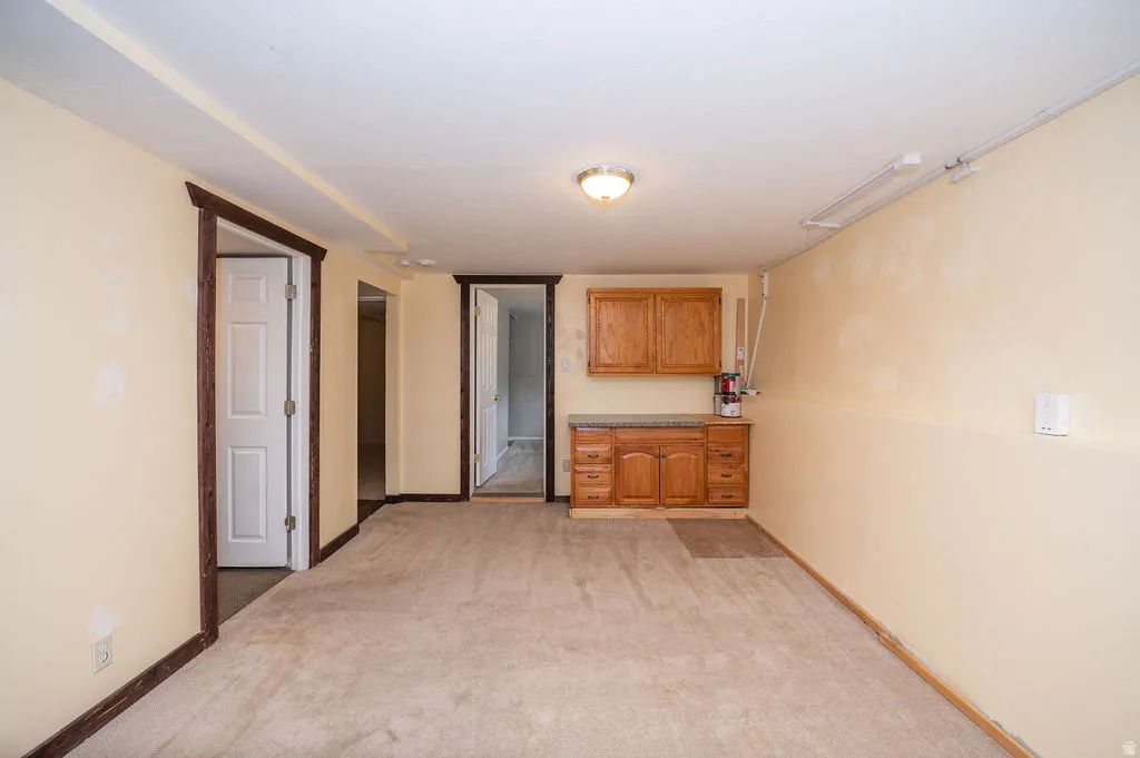 Bar featuring light colored carpet and wood finish cabinets