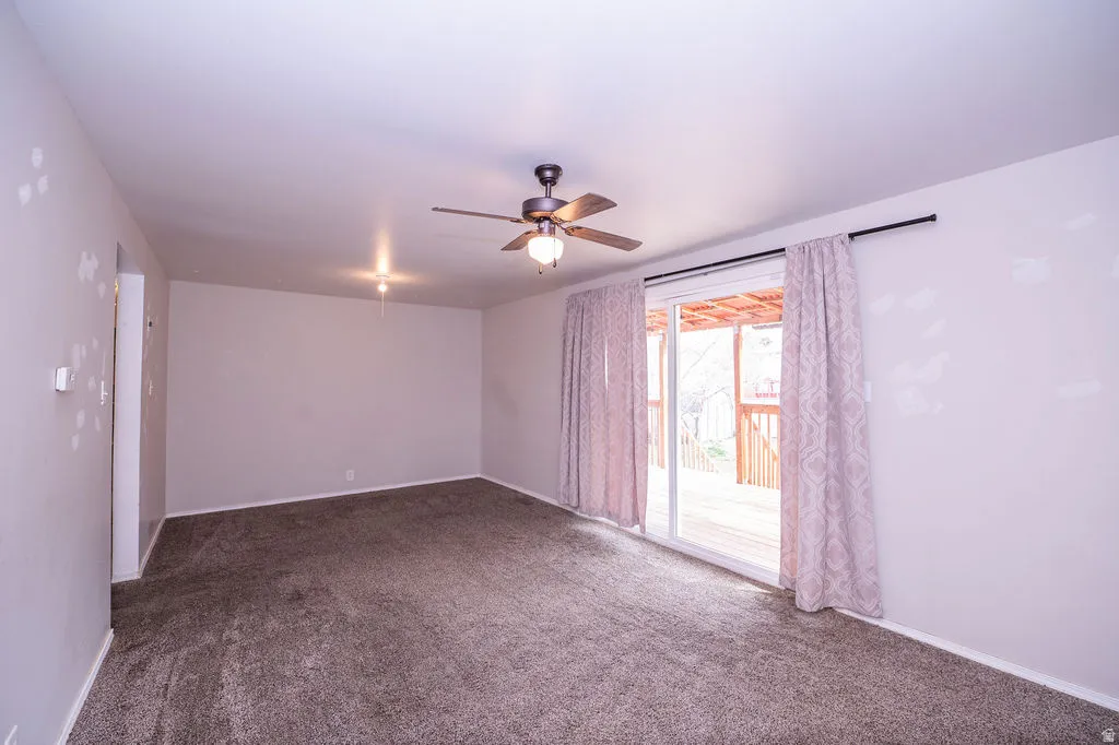 Empty room with dark colored carpet and ceiling fan