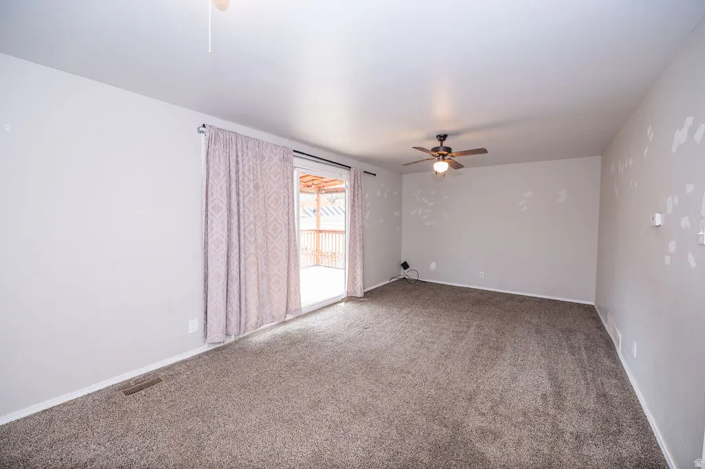 Spare room featuring a ceiling fan and light carpet