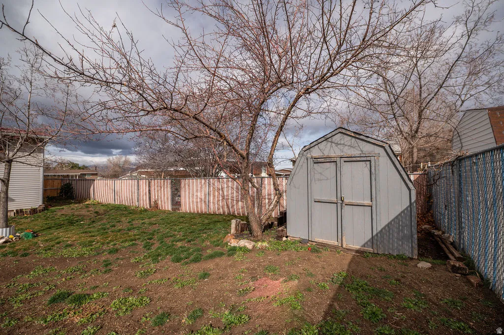 Fenced backyard featuring a shed