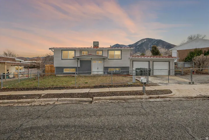 Raised ranch with driveway, a chimney, a garage, a fenced front yard, and a mountain view