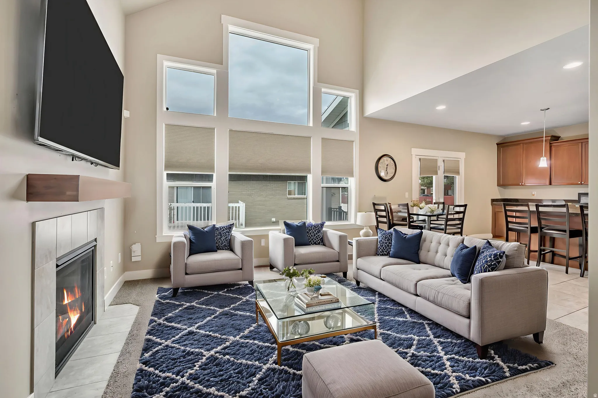 Living room with a tile fireplace, a high ceiling, and recessed lighting