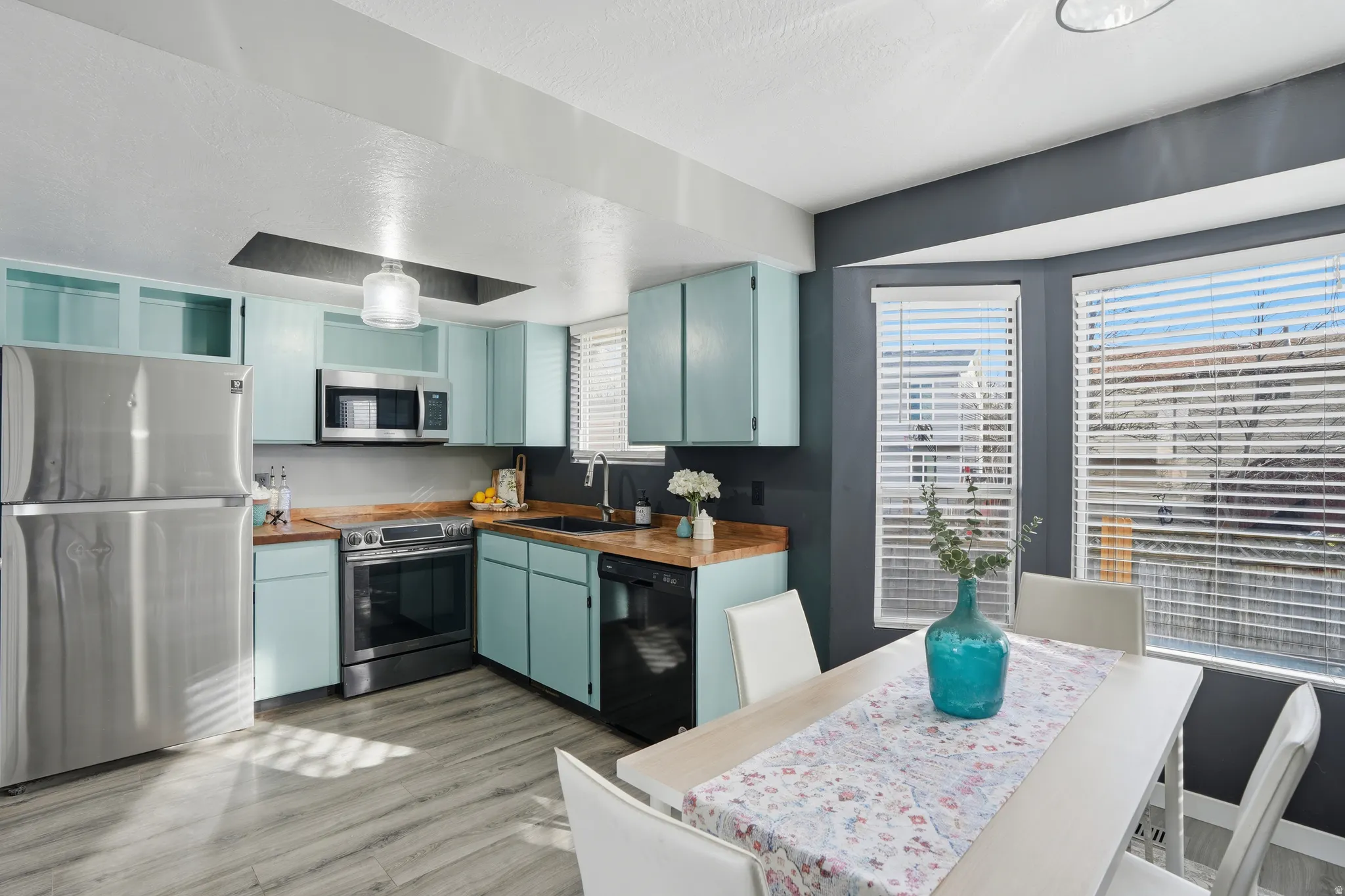 Kitchen with stainless steel appliances, butcher block counters, wood finished floors, and blue cabinets